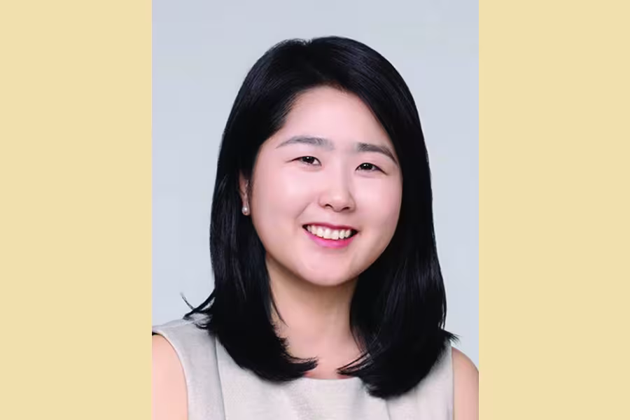 Portrait of pianist and organist Hae Won Jang smiling at the camera, with shoulder-length black hair and wearing a light-colored sleeveless top.