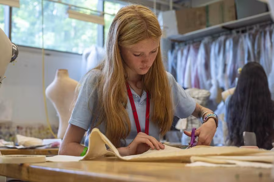 A fashion student cuts material for a garment. 