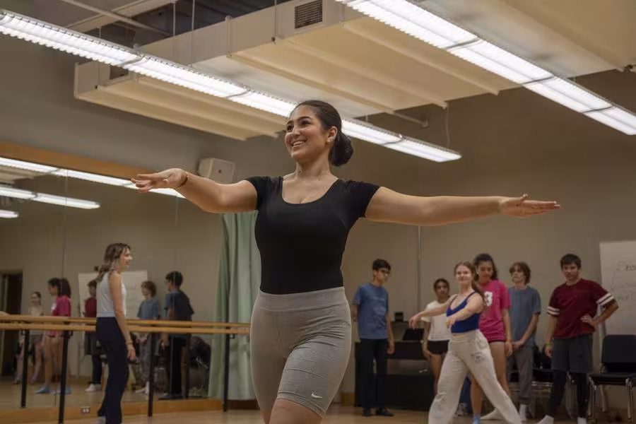 A high school musical theatre student smiles during a dance class.