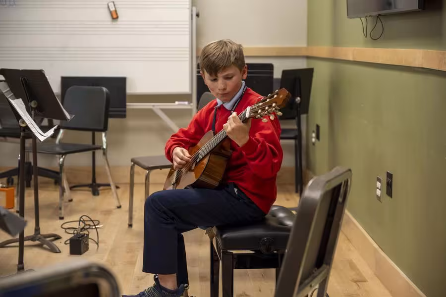 A junior guitarist participates in a classical guitar workshop. 