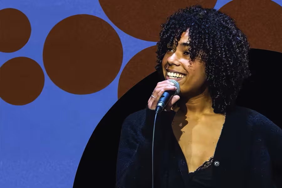 Jazz vocalist smiling while singing into a microphone.