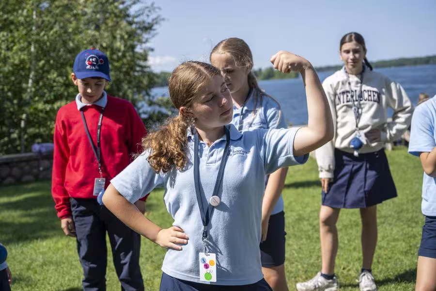An arts camp student gives a confident flexing pose to show their strength