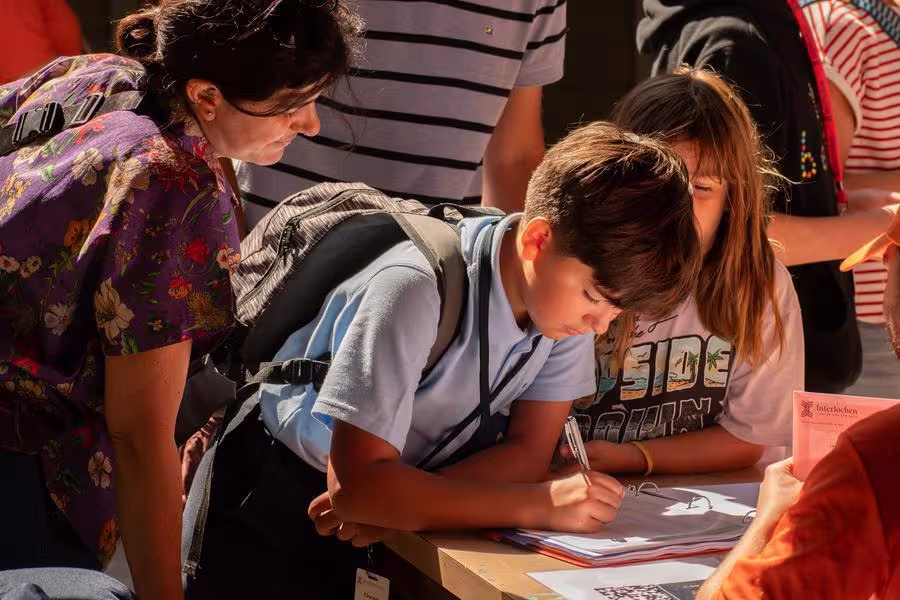 An arts camp student fills out a form with their parent