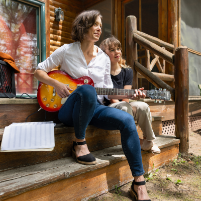 Mother playing guitar with her daughter next to her