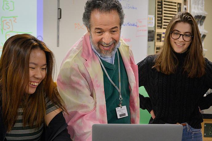 students and faculty smile at a computer in physics class at interlochen arts academy