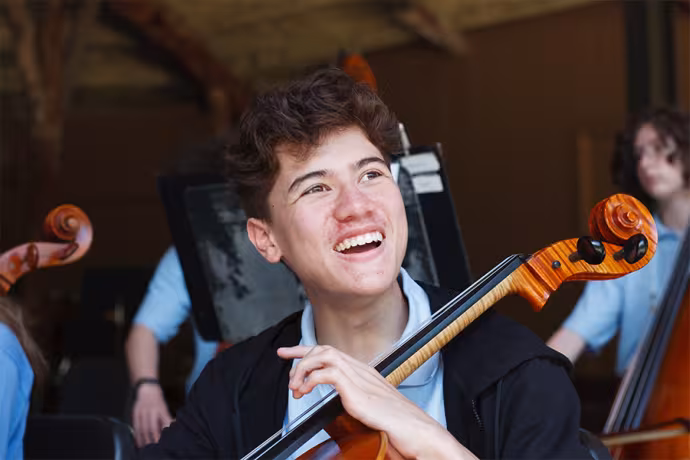 A cellist smiles during a World Youth Symphony Orchestra rehearsal. 
