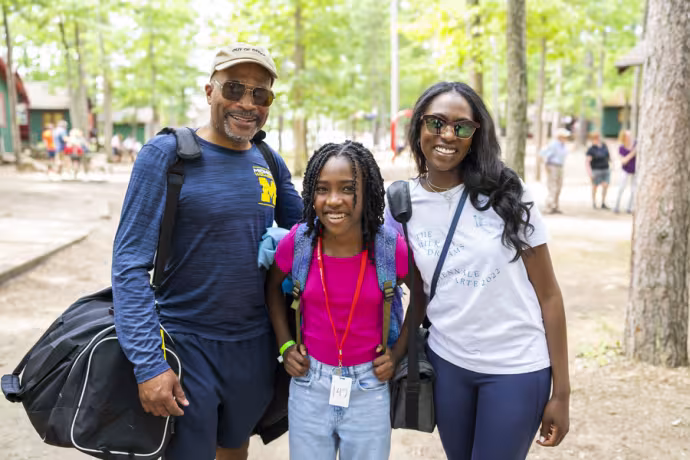 A young Camp student poses with parents.