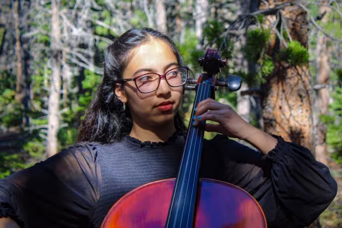 Meena Karimi wears black attire while she performs in the woods.
