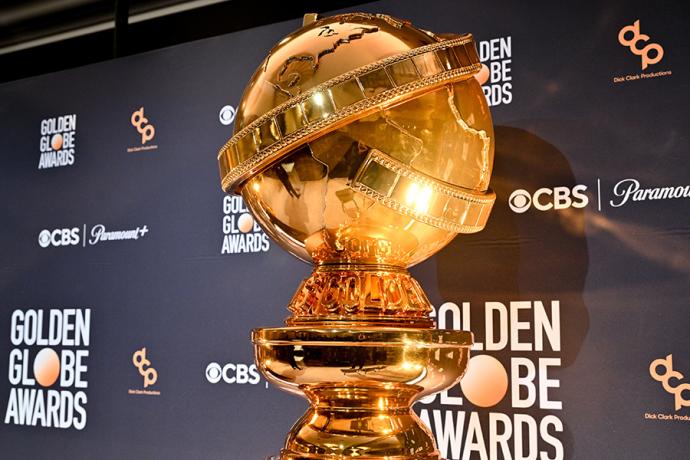 A Golden Globe Award in front of a step-and-repeat banner