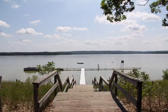 Beautiful image of wooden steps leading down to a lake under a sunny sky.