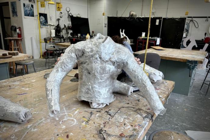 A gray sculpted torso mold sits on a wooden table.