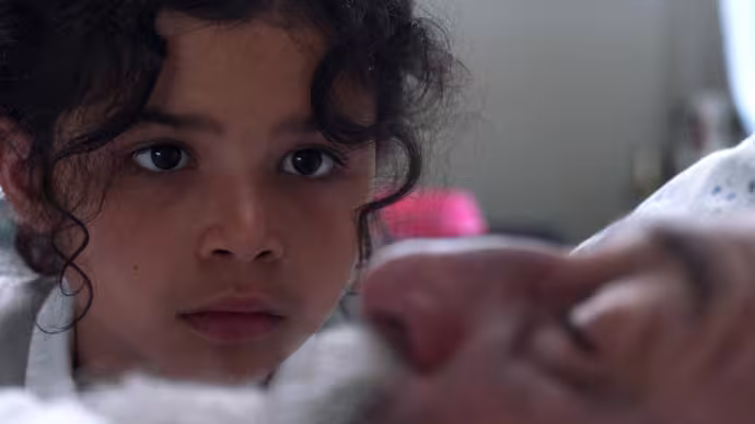 A young girl looks intently at a man's face