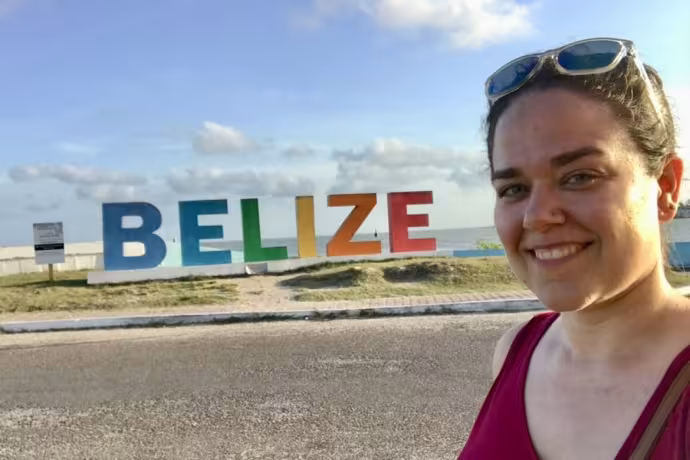 Lauren Hunt in front of a colorful "BELIZE" sign