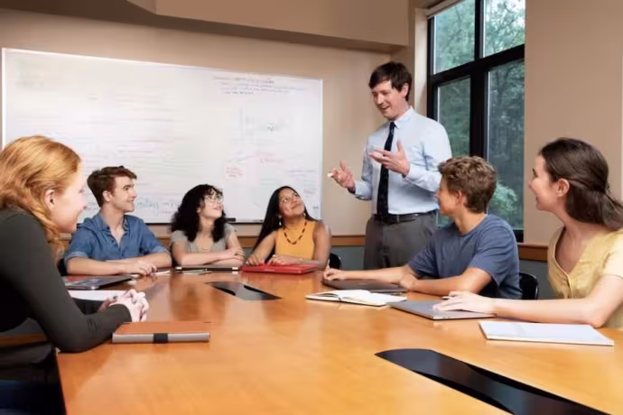A teacher speaks to a group of seated students. 