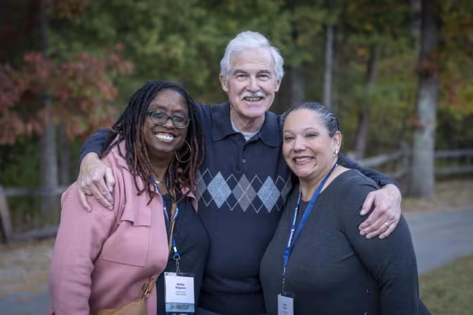 Three alumni stand outdoors.