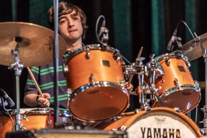 A popular music student plays drums.