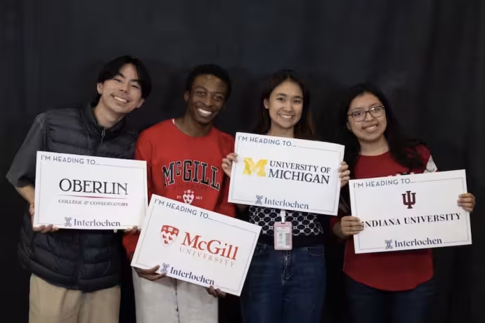 Students show off signs from the colleges to which they have been admitted.