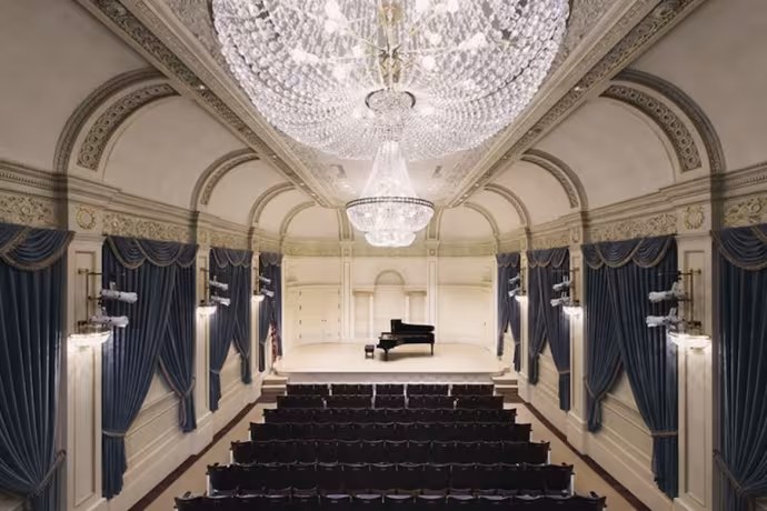 Shot of a stunning, chandelier-hung recital hall with a piano onstage.