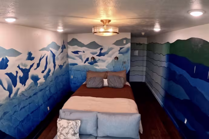 The image depicts a hotel room with glacier murals on the walls.