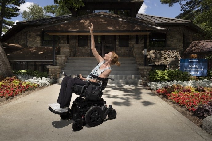 Ginger Lane holds a dance pose in her wheelchair in front of the Maddy Administration Building