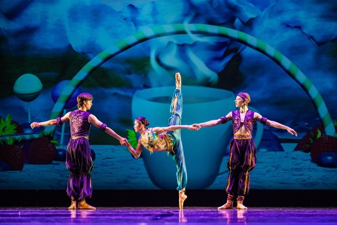 Three dancers dressed in stylized Arabian costumes pose onstage.