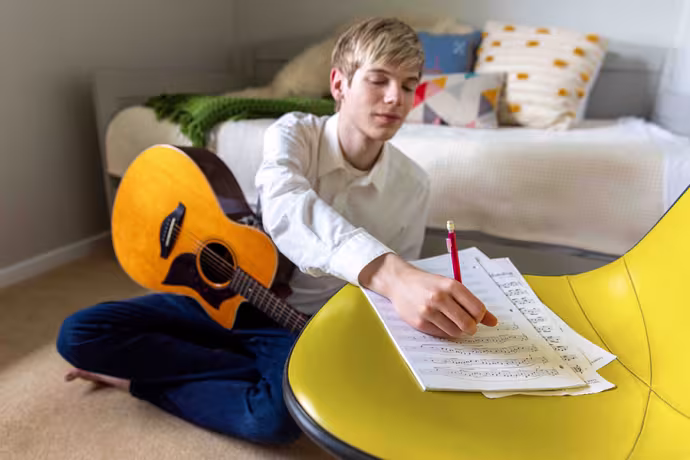 A guitarist takes notes on staff paper
