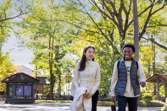 Two smiling Academy students walk on through Interlochen's campus