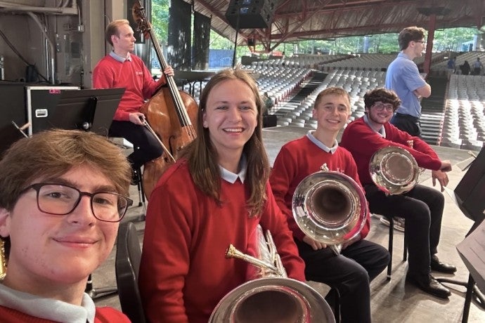 A smiling row of students with brass instruments.