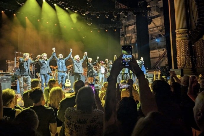 Paul Simon's band takes a bow at the end of a show in front of a cheering audience.