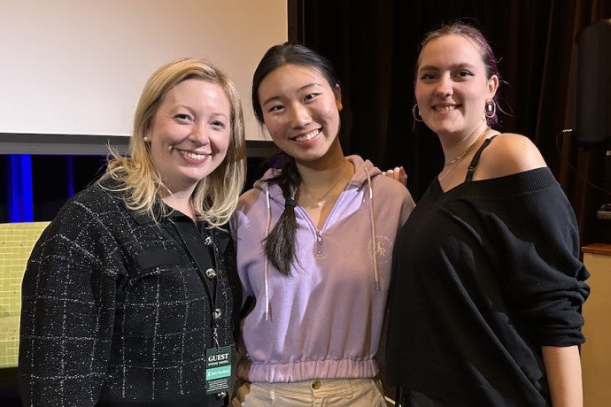 A guest artist poses with two students for a picture.