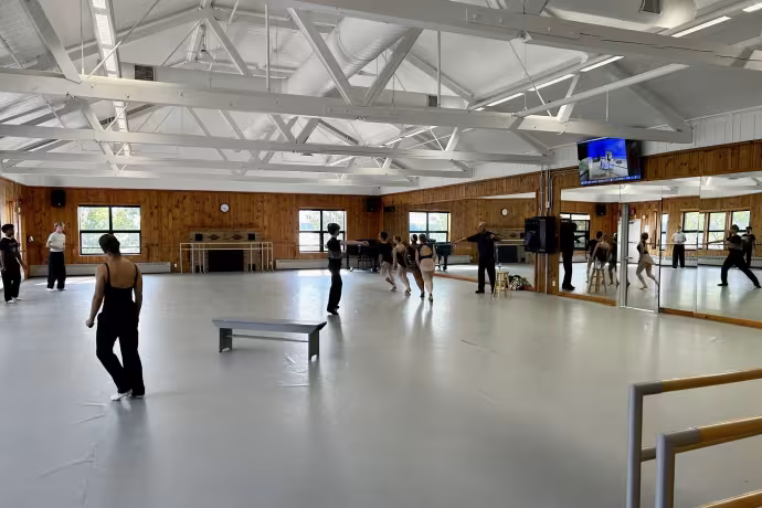 Dancers scatter around a studio space with large mirrors.