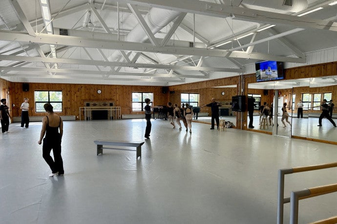 Dancers scatter around a studio space with large mirrors.
