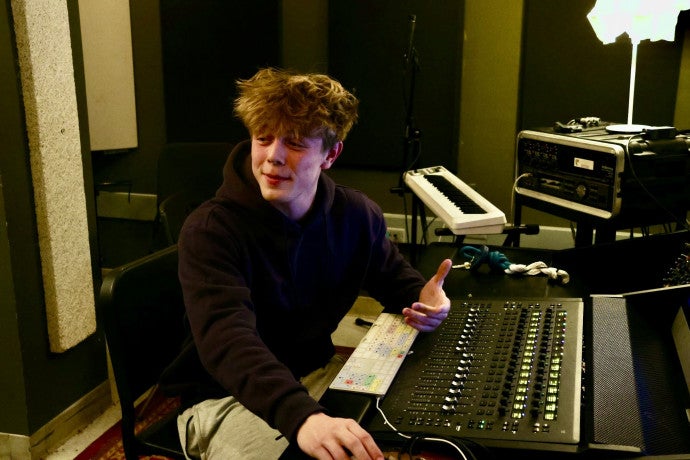 A student gestures while sitting at the piano. 
