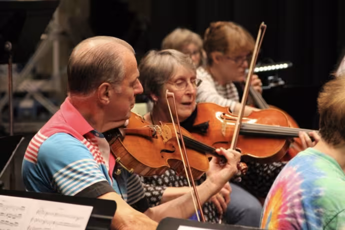 Musicians play violins in a string orchestra.