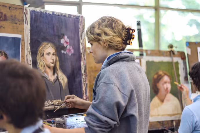 A student works on a painted self portrait 
