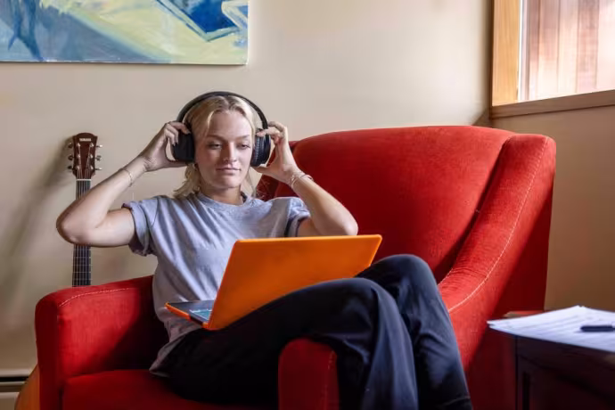 A music student sits down at their laptop for an online class