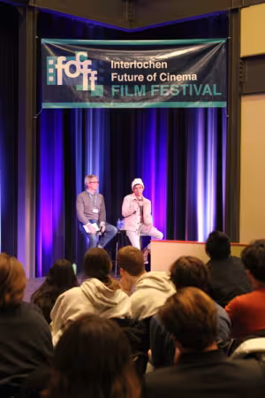 Two filmmakers address an audience of students.