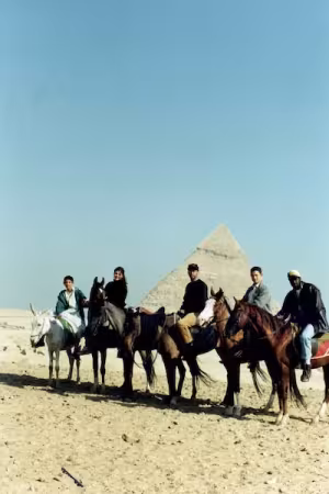 Five mounted riders stand in front of a pyramid.