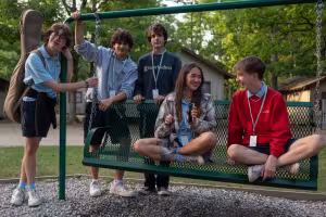 High school students sit and talk on a swing outside.