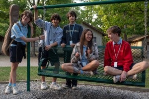 High school students sit and talk on a swing outside.