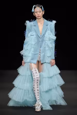 A model wears a light blue garment featuring layers of tulle.