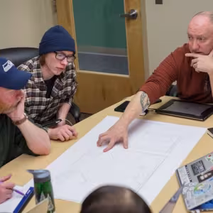Stephen John (top right) explains his class's set design for As You Like It to Instructor of Theatre Andy McGinn (bottom left).