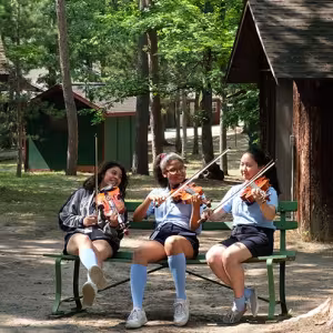 Three violinists rehearse on a bench