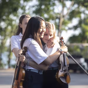 Girls hugging with violins