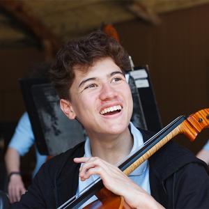A cellist smiles during a World Youth Symphony Orchestra rehearsal. 