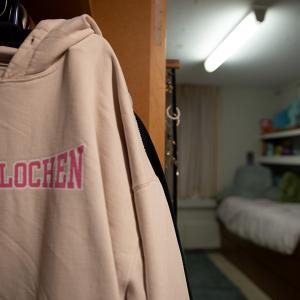 A pink "Interlochen" hooded sweatshirt hangs in a student's dorm room closet.