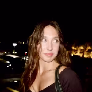 Picture of senior student Nettie James-Drost with long brown hair in front of a large city at night.