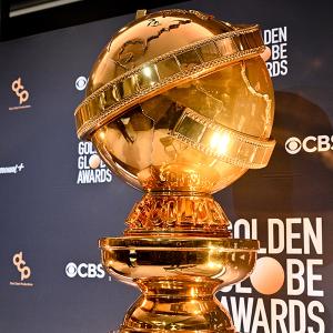 A Golden Globe Award in front of a step-and-repeat banner