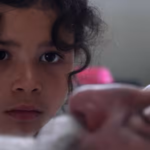 A young girl looks intently at a man's face