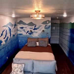 The image depicts a hotel room with glacier murals on the walls.